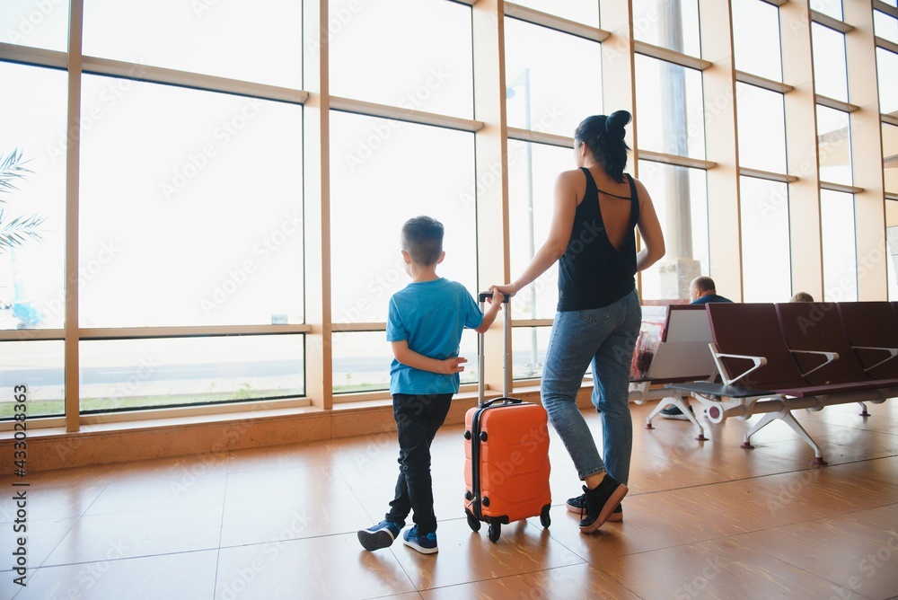 Family at airport before flight. Mother and son waiting to board at departure gate of modern international terminal. Traveling and flying with children. Mom with baby and toddler boarding airplane. Family at airport before flight. Mother and son waiting to board at departure gate of modern international terminal. Traveling and flying with children. Mom with baby and toddler boarding airplane.