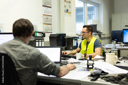 Büroarbeit - Mehrere Mitarbeiter arbeiten am Schreibtisch vor ihren PC's