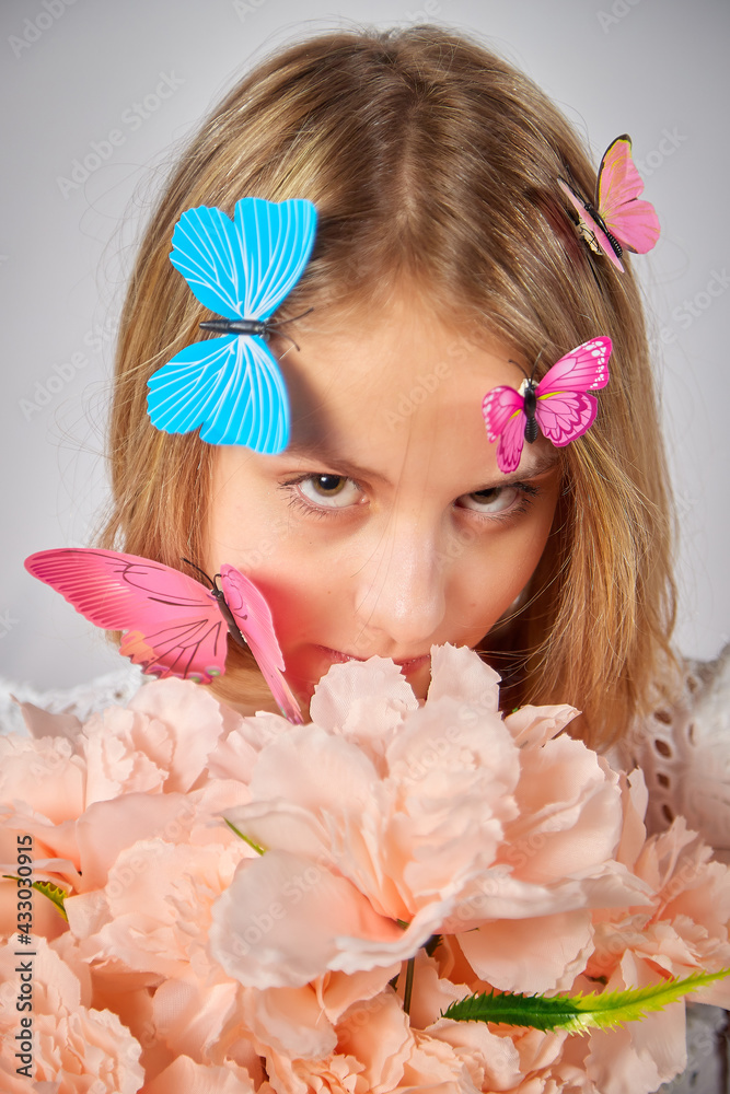 Young teen blonde girl with flowers and butterfly in studio with white background. Spring portrait. Healthy skin and natural makeup for teenage girls Young teen blonde girl with flowers and butterfly in studio with white background. Spring portrait. Healthy skin and natural makeup for teenage girls