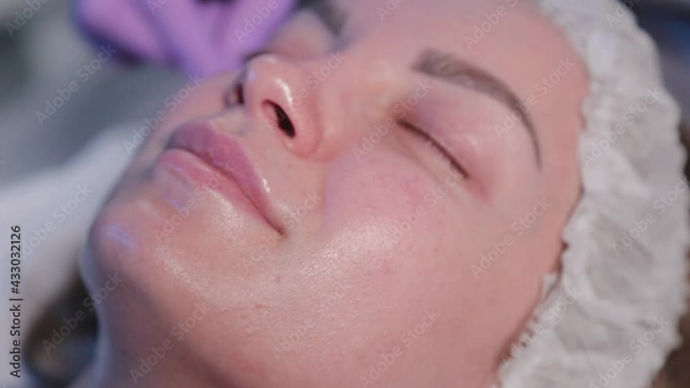 Woman beautician applies liquid to woman's face with cotton swabs. Woman beautician applies liquid to woman's face with cotton swabs.