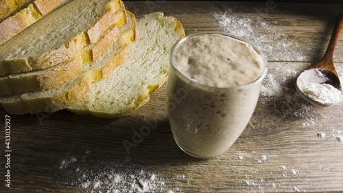 Active sourdough culture inside a glass cup on a baker's table. Time lapse footage shows the process of fermentation with rising and falling of the starter culture and bubbling of CO2 in the process. 