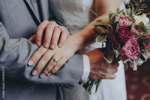 stylish bridal couple together, hands with wedding rings close up