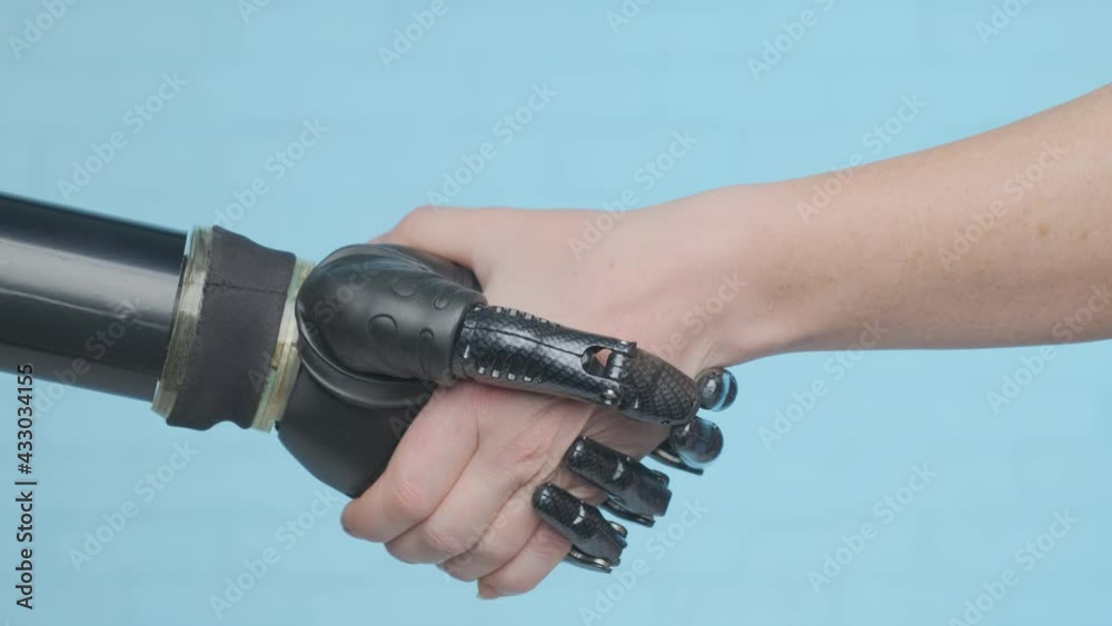 Handshake of humanoid robot arm and human hand on blue background close-up. Concept of interaction of artificial intelligence and human mind. Handshake of humanoid robot arm and human hand on blue background close-up. Concept of interaction of artificial intelligence and human mind.