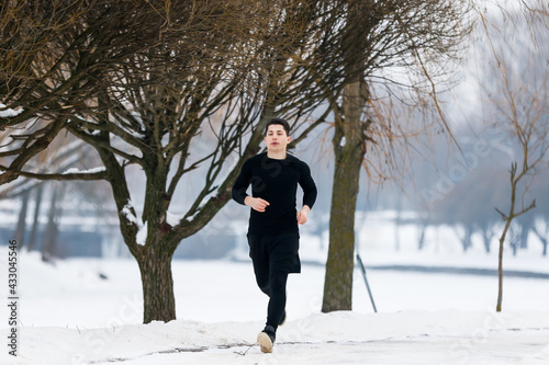 Young man goes jogging in winter while doing sports.