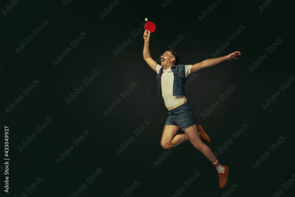 Young caucasian man playing tennis isolated on black studio background in retro style, action and motion concept