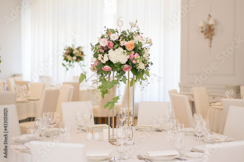Photos Centerpiece made of green leaves and fresh flowers stands on the dinner table