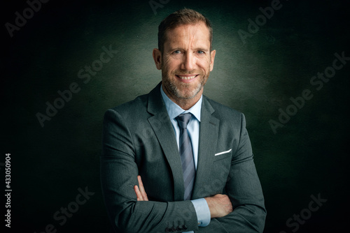 Executive businessman studio portrait while standing at isolated dark background