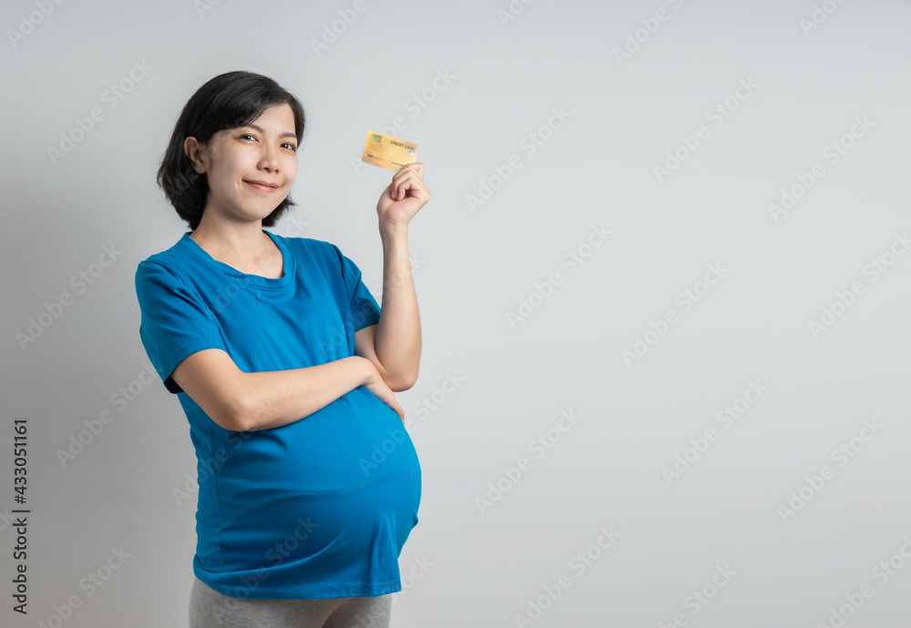 Smiling Asian Pregnant woman wearing blue t-shirt holding credit bank card looking camera on isolated background studio. Smiling Asian Pregnant woman wearing blue t-shirt holding credit bank card looking camera on isolated background studio.