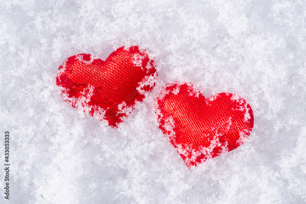 Fototapeta premium Close-up photo of two red cloth hearts on a white snow. Concept of love, devotion