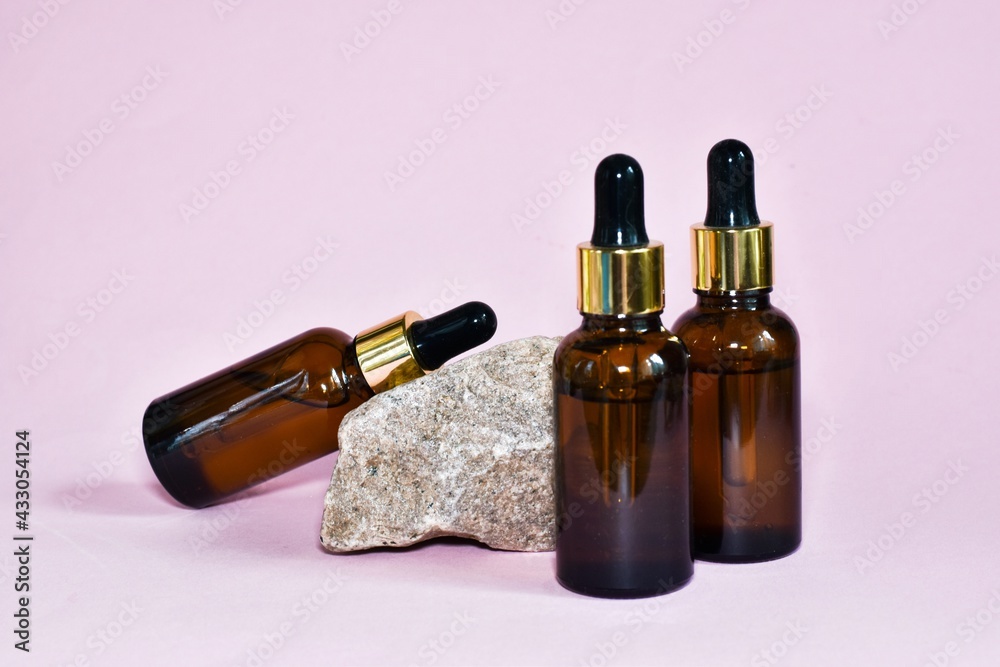 Bottles with pipette on stone on a pink background. Cosmetic Beauty Concept. Copy space. Mock up. Skin care, moisturizing beauty product. Bottles with pipette on stone on a pink background. Cosmetic Beauty Concept. Copy space. Mock up. Skin care, moisturizing beauty product.