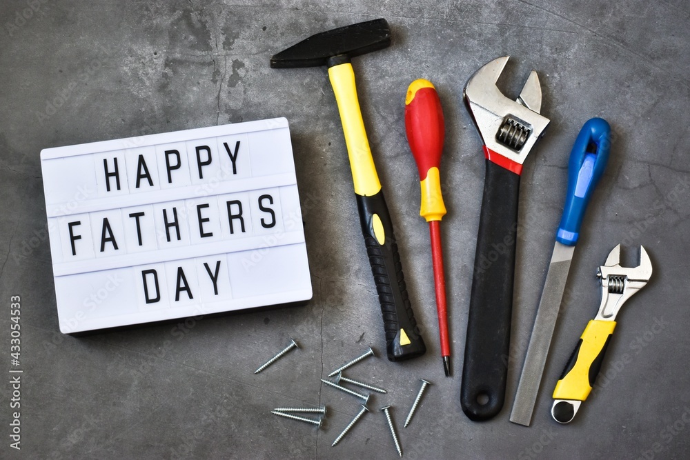 Light box with the inscription HAPPY FATHER'S DAY with construction tools on a gray concrete background. Holiday concept.
Flat lay.