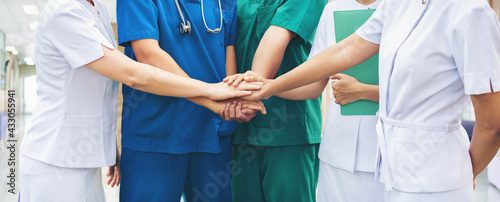 Cooperation of people in the medical community teamwork with a hands together between the doctor in the green, blue uniform and nurses in white dress at hospital. Fight covid 19 virus healthy concept.
