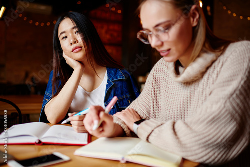 Thoughtful women doing homework in cafe