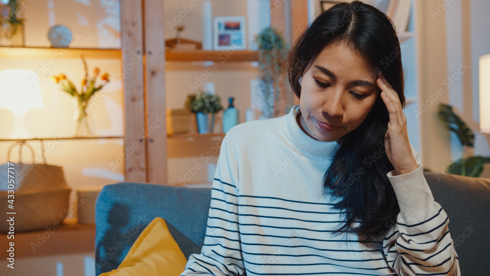 Thoughtful Asia lady suffering from insomnia sit at sofa in living room at house night with feel lonely, Sad depressed teenager spend time alone stay at home, Social distance, Coronavirus quarantine. Thoughtful Asia lady suffering from insomnia sit at sofa in living room at house night with feel lonely, Sad depressed teenager spend time alone stay at home, Social distance, Coronavirus quarantine.