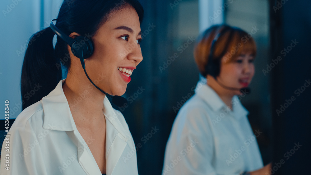 Millennial Asia young call center team or customer support service executive using computer and microphone headset working technical support in late night office. Telemarketing or sales job concept. Millennial Asia young call center team or customer support service executive using computer and microphone headset working technical support in late night office. Telemarketing or sales job concept.