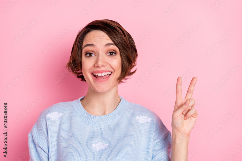 Photo of pretty cheerful lady toothy smile fingers show v-sign wear sweater isolated on pink color background Photo of pretty cheerful lady toothy smile fingers show v-sign wear sweater isolated on pink color background