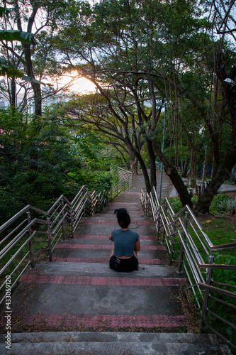curly latin girl relax on tropical road, curly latin woman sitting in a tropical park