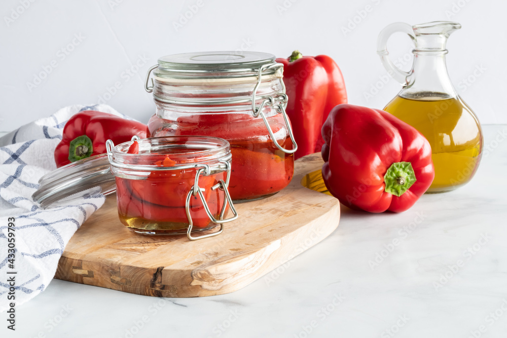 Roasted red peppers on a wooden cutting board, surrounded by fresh red peppers and olive oil. Roasted red peppers on a wooden cutting board, surrounded by fresh red peppers and olive oil.