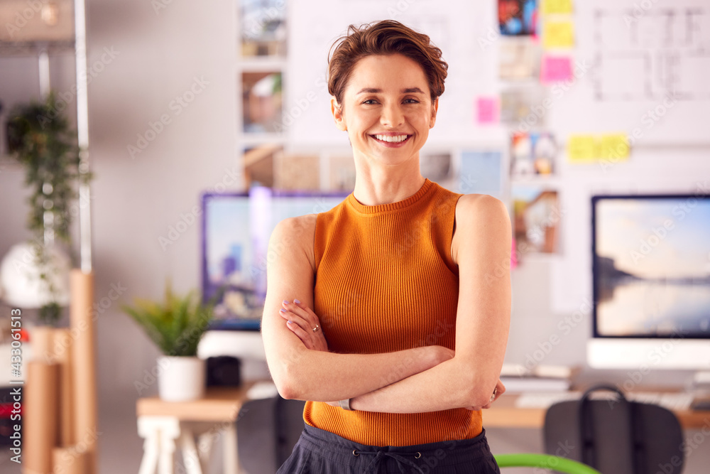 Portrait Of Smiling Female Architect In Office Standing By Desk With Folded Arms