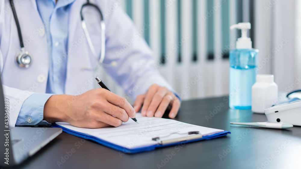Medical concept a male doctor wearing a mask writing prescription to patient for recovering from Coronavirus (COVID-19) at his modern clinic Medical concept a male doctor wearing a mask writing prescription to patient for recovering from Coronavirus (COVID-19) at his modern clinic
