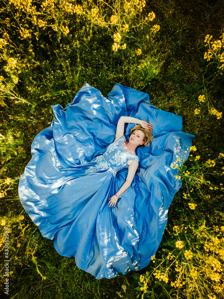 Fashion beautiful young woman blue dress and yellow flowers posing outdoor rapeseed field Fashion beautiful young woman blue dress and yellow flowers posing outdoor rapeseed field