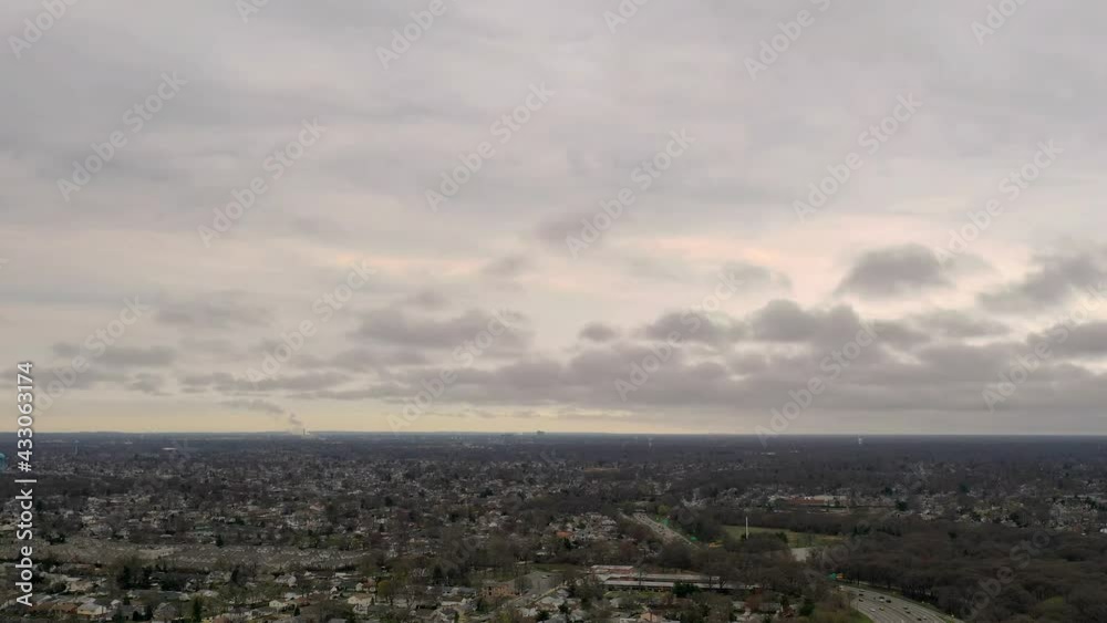 A high angle aerial time-lapse near a highway on a cloudy day. The shot was taken with a drone hovering, as the clouds move towards the left. There is light traffic on the highway below. A high angle aerial time-lapse near a highway on a cloudy day. The shot was taken with a drone hovering, as the clouds move towards the left. There is light traffic on the highway below.