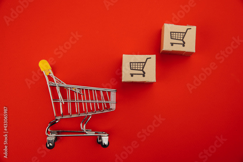 Shopping cart with boxes isolated on red