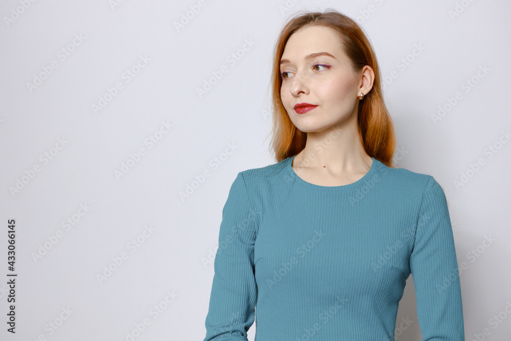 Portrait of an attractive red-haired woman in a blue dress on a white background. Copy space Portrait of an attractive red-haired woman in a blue dress on a white background. Copy space