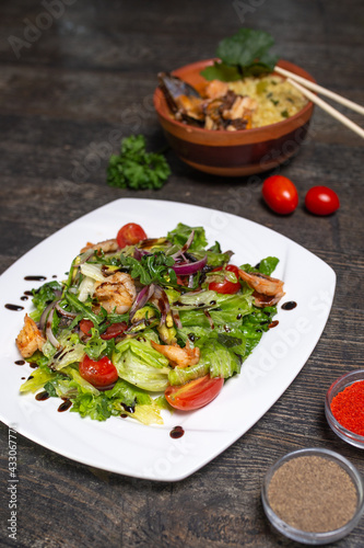 Oriental kitchen salad with shrimps and vegetables on a wooden background