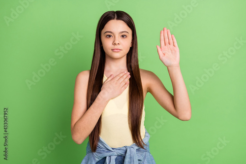 Quadro su tela Photo of young beautiful serious little girl hold hand chest giving oath honorab