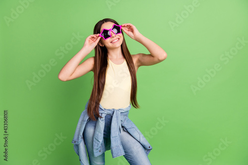 Photo of young preteen girl happy positive smile hands touch sunglass isolated over green color background
