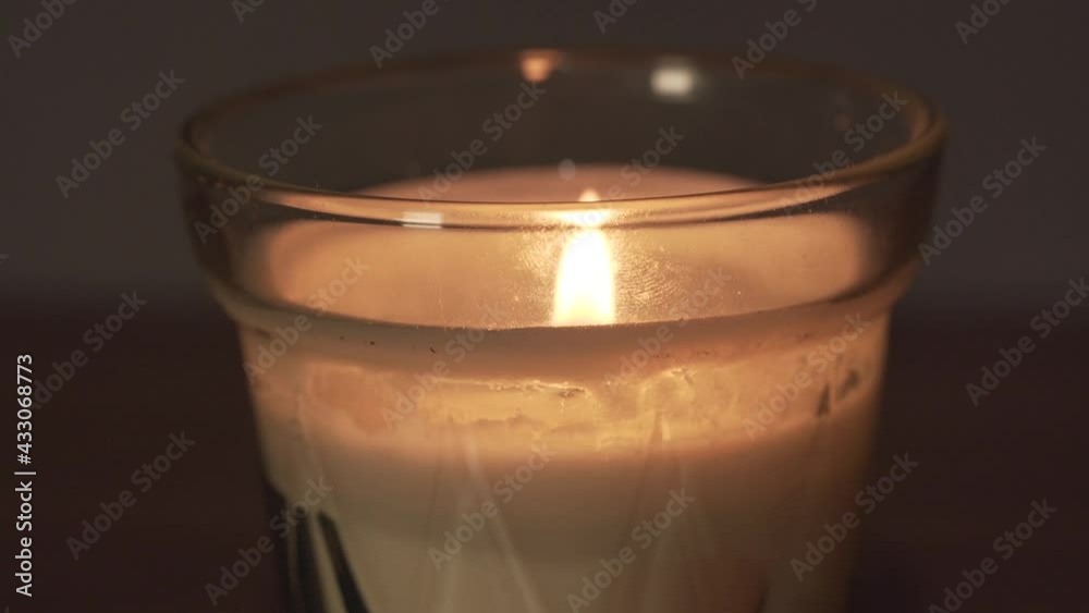 Close macro view of glass white wax candle and bright yellow flame at home. Decoration object Close macro view of glass white wax candle and bright yellow flame at home. Decoration object