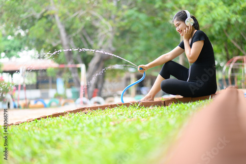 A pregnant woman wearing a black dress stood happily watering the plants in the morning.