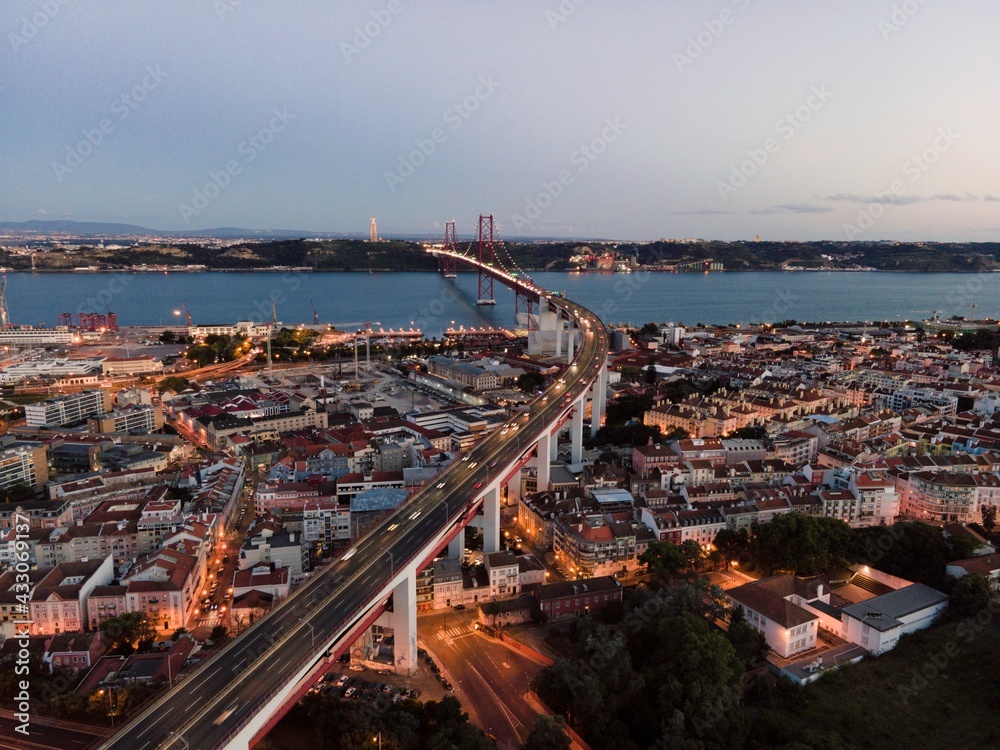 Aerial view of April 25th bridge with Christ the King statue (Cristo Rei) in background at sunset, view of Lisbon skyline at night, Alcântara, Lisbon, Portugal.