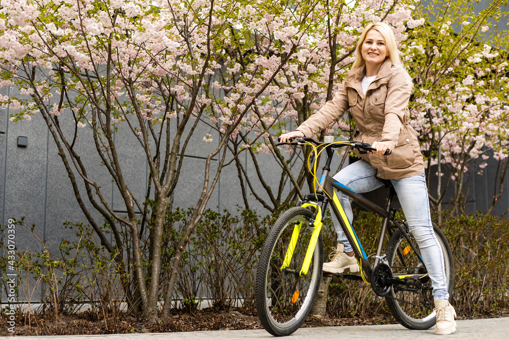 Lovely young woman posing with bike on the street of city, on sunny day