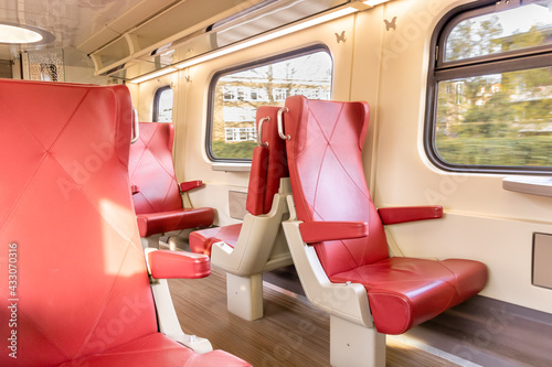 First Class train interior with red-leather seats. bright sunlight while travelling. 