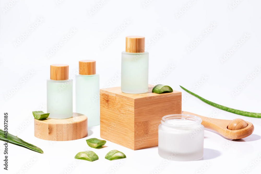 Natural plant based cosmetics with aloe on wooden podiums in reusable bottles with plant shadow on background