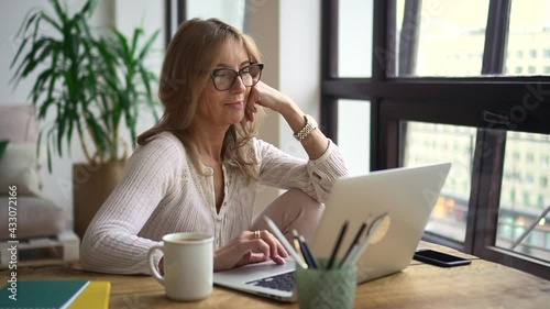Businesswoman using laptop and sitting at table in home office during pandemic.