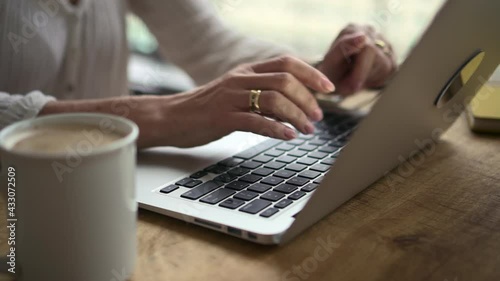 Businesswoman typing and using laptop at table during working day at home office.