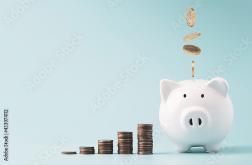 Coins falling to white piggy saving ,  Financial and money deposit concept. photo