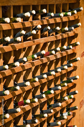 Opened wine bottles stacked in wooden racks in restaraunt. Lots of corked bottles.