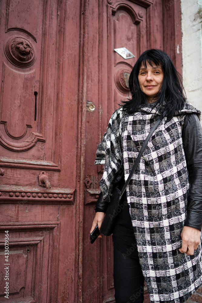 Fototapeta premium portrait of a woman in front of the old red door in Europe
