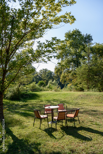 Empty garden table and chairs on green grass at the park