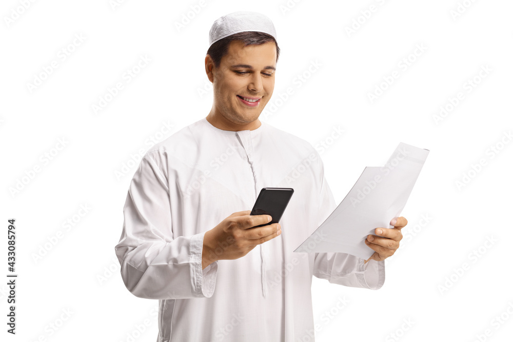 Young muslim man in white clothes using a smartphone and holding a paper document Young muslim man in white clothes using a smartphone and holding a paper document