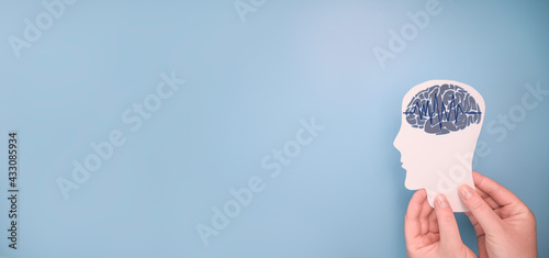 Female hands holding paper cutout head and brain.  Epilepsy and Alzheimer awareness, seizure disorder, mental health concept photo