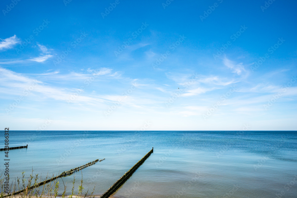 A view of the beach and a row of breakwaters in the foreground. A view of the beach and a row of breakwaters in the foreground.