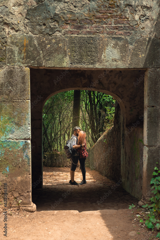 Young woman with Asian features and pink hair posing for the camera in the forest with medieval ruins. Caminata concept, travel and tourism concept