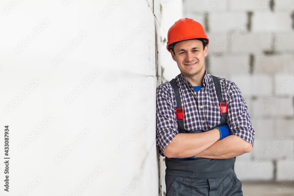Caucasian construction worker with safety helmet on head in vest standing with arms crossed at construction site and looking at camera. Caucasian construction worker with safety helmet on head in vest standing with arms crossed at construction site and looking at camera.