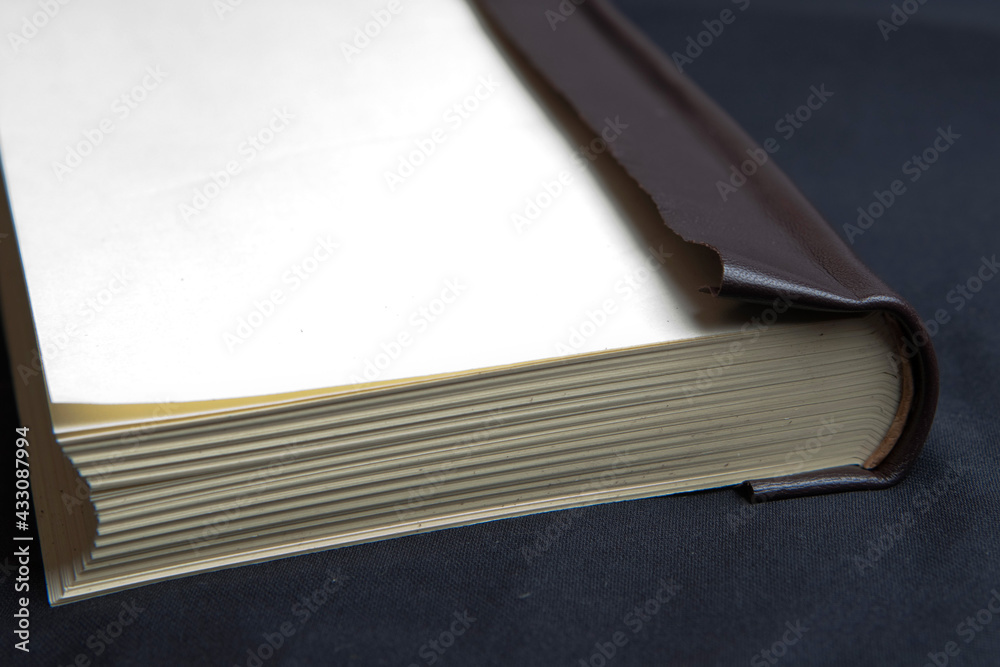 The process of book binding; leather book spine, without the hard cover. Black background