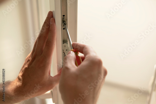 Tableau sur toile A man straightens a plastic window or door with a screwdriver, man's hands close-up
